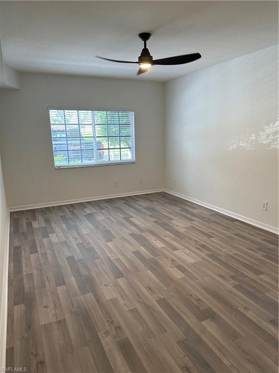 27103 Matheson Avenue, Unit 103 Bonita Springs, FL 34135 - Photo 10 of 29 Unfurnished room with a textured ceiling, dark wood-type flooring, and ceiling fan