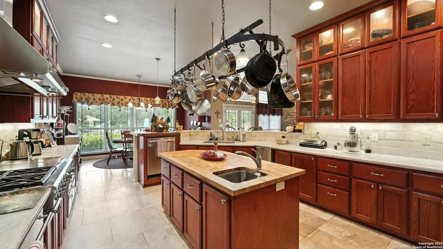 a kitchen with stainless steel appliances granite countertop a sink a stove and a wooden cabinets