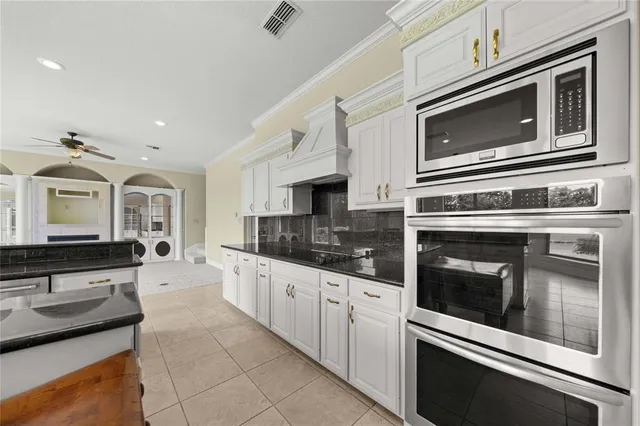 a kitchen with stainless steel appliances granite countertop a stove a sink a refrigerator a microwave and white cabinets