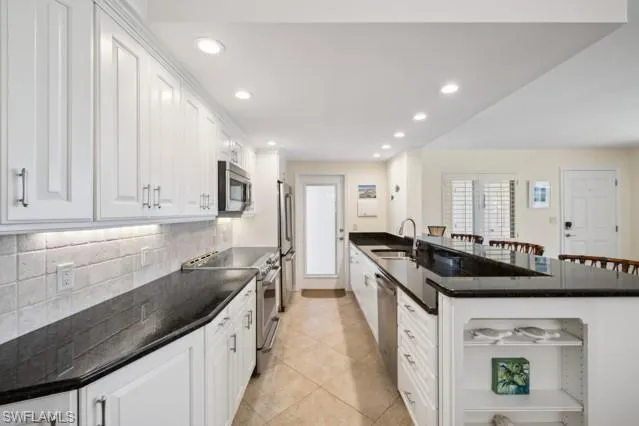 a kitchen with stainless steel appliances granite countertop a dining table chairs and a refrigerator
