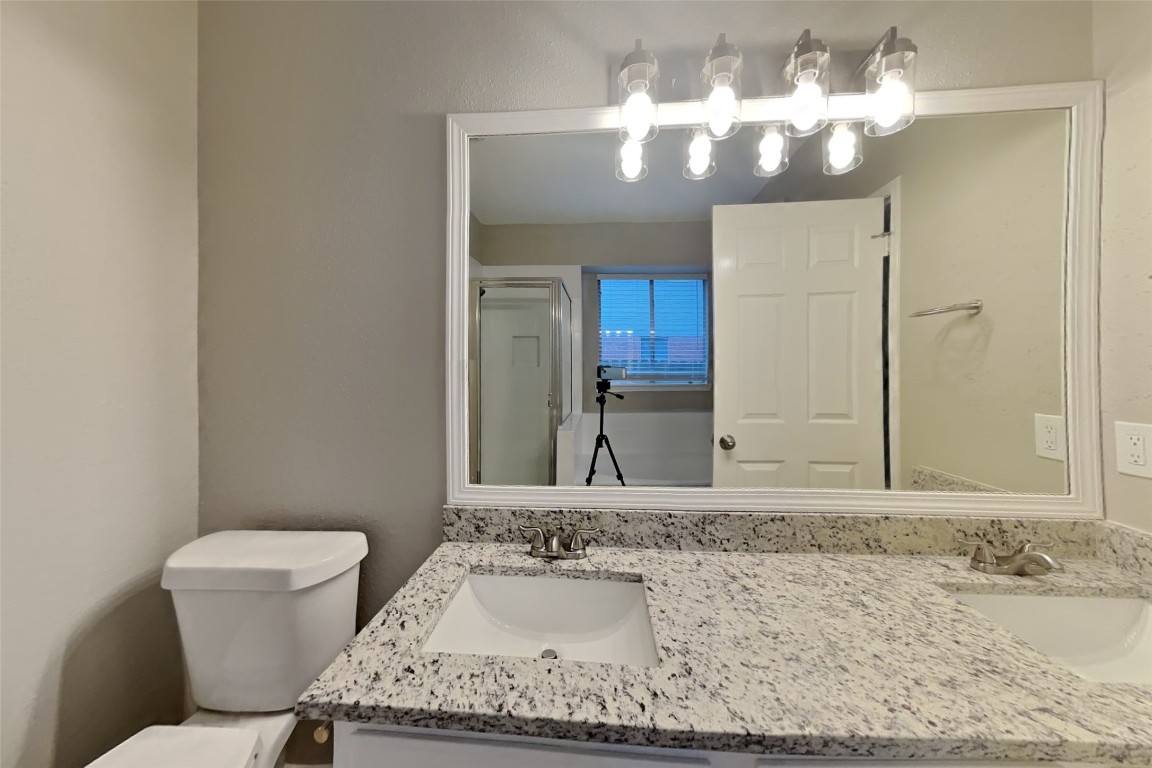 16411 Willingham Way Houston, TX 77095 - Photo 10 of 21 a bathroom with a granite countertop sink a toilet and mirror