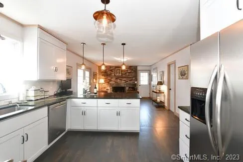 a kitchen with stainless steel appliances granite countertop a refrigerator a oven a sink dishwasher and white cabinets with wooden floor
