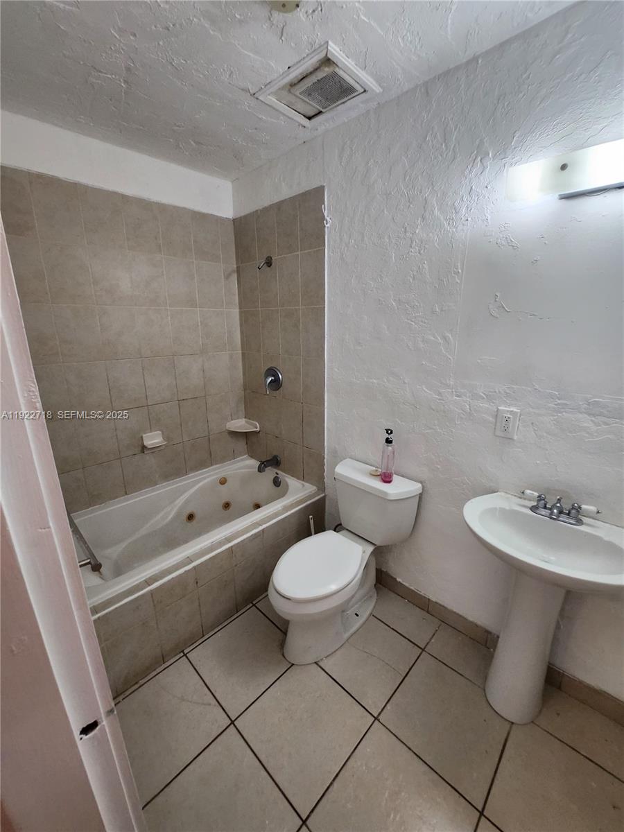 2129 Taylor Street Hollywood, FL 33020 - Photo 9 of 9 a bathroom with a toilet sink a mirror and bathtub