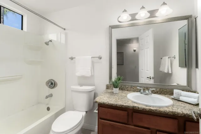 a bathroom with a granite countertop sink toilet a mirror and shower