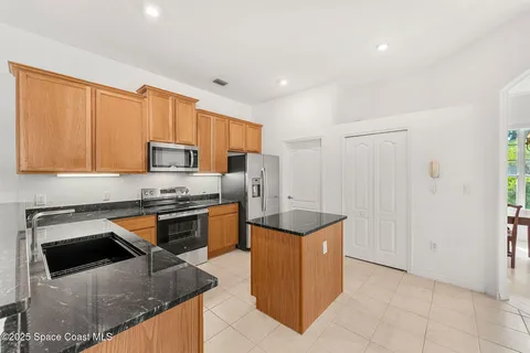 a kitchen with white cabinets granite counter and chairs