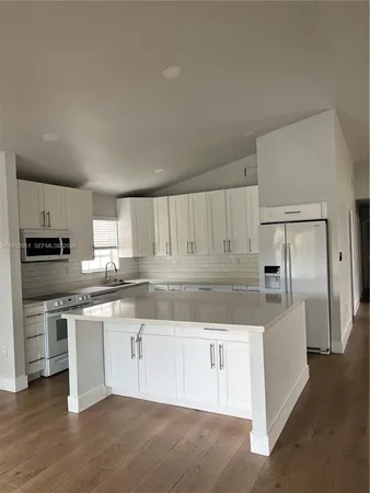 a kitchen with stainless steel appliances granite countertop a refrigerator and a stove top oven