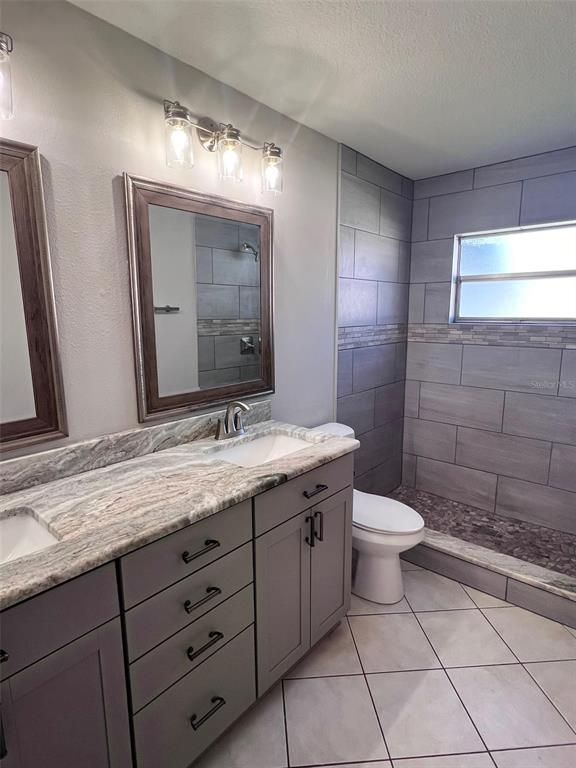 4317 Chipmunk Drive New Port Richey, FL 34653 - Photo 14 of 23 a bathroom with a granite countertop sink a toilet and a mirror