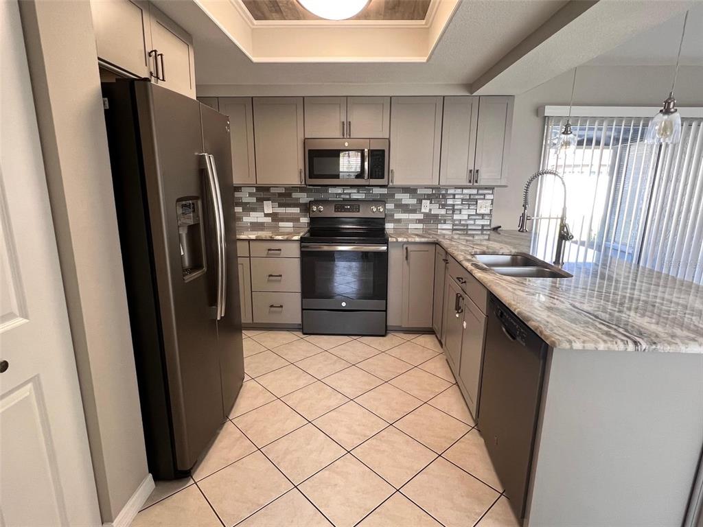 4317 Chipmunk Drive New Port Richey, FL 34653 - Photo 4 of 23 a kitchen with stainless steel appliances a refrigerator stove microwave and sink