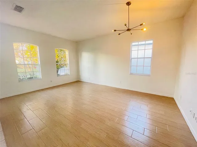 a view of an empty room with a window and wooden floor