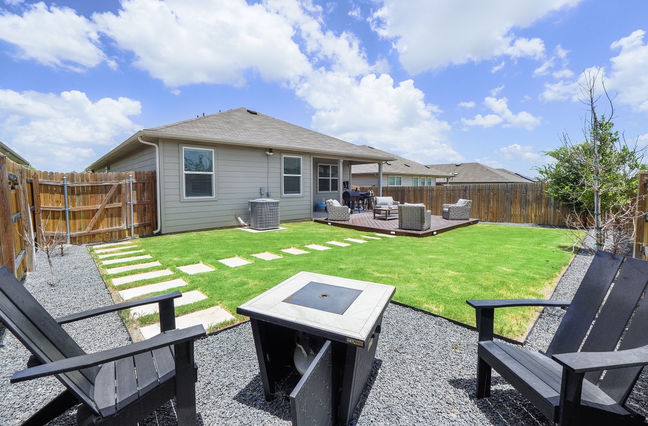217 Evergreen Sumac Loop Kyle, TX 78640 - Photo 2 of 20 A vibrant backyard with a cozy deck and fire pit offers ample space for outdoor relaxation.