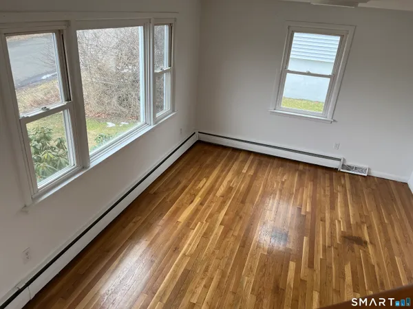 a view of empty room with wooden floor and windows