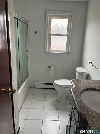 a bathroom with a granite countertop sink a toilet a mirror and tub