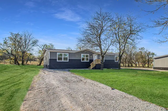 a view of a yard in front of a house with large trees