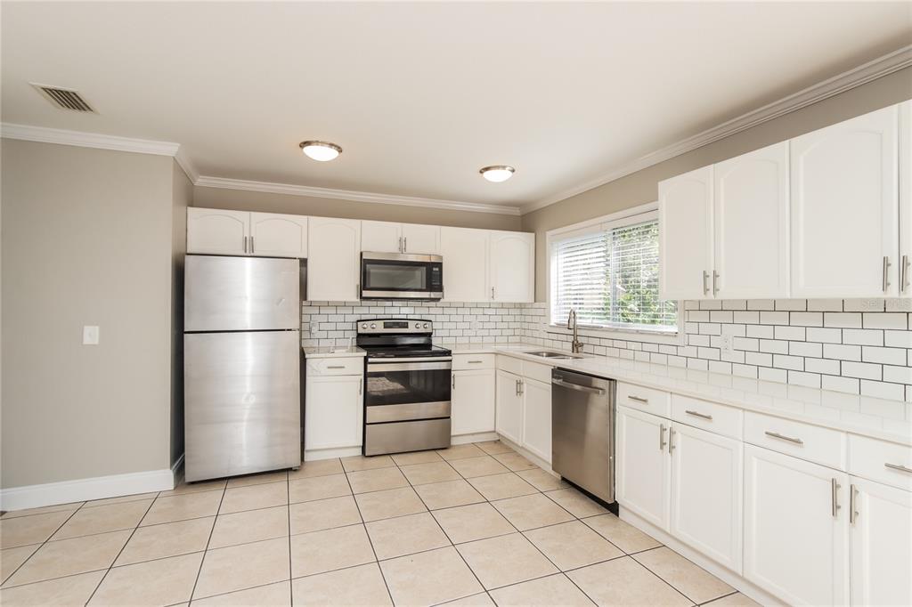 481 Ralwood Lane Northeast Palm Bay, FL 32907 - Photo 7 of 18 a kitchen with white cabinets stainless steel appliances and a window
