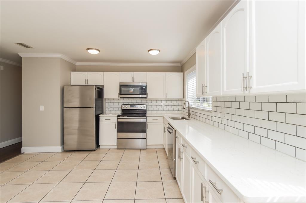 481 Ralwood Lane Northeast Palm Bay, FL 32907 - Photo 8 of 18 a kitchen with a sink a refrigerator and a stove top oven with white cabinets