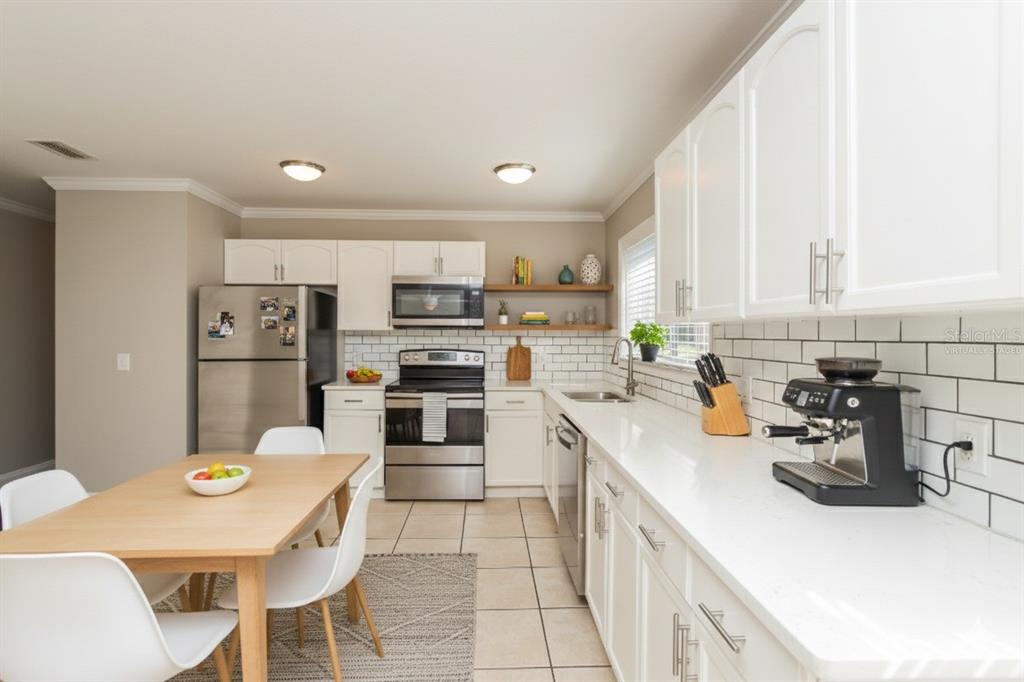 481 Ralwood Lane Northeast Palm Bay, FL 32907 - Photo 9 of 18 a kitchen with a sink a stove a refrigerator and white cabinets