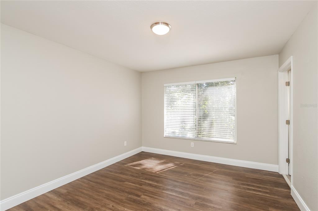 481 Ralwood Lane Northeast Palm Bay, FL 32907 - Photo 10 of 18 an empty room with wooden floor and windows