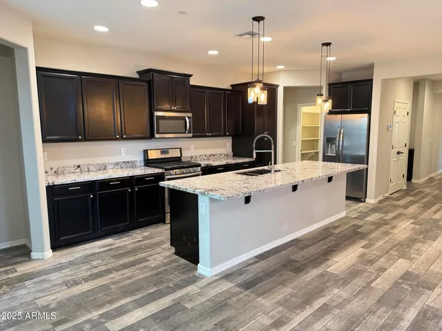 a kitchen with stainless steel appliances kitchen island granite countertop a stove top oven a sink and a refrigerator