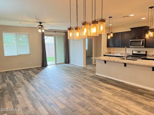 a view of a kitchen with kitchen island stainless steel appliances wooden floor and chandelier