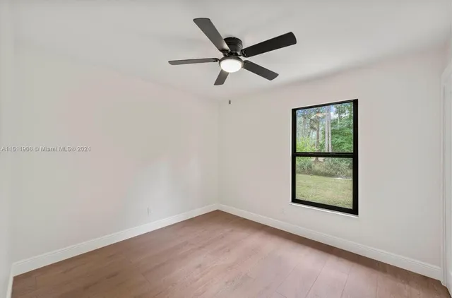 an empty room with ceiling fan and window