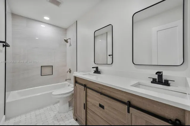 a bathroom with a double vanity sink a toilet and a bathtub