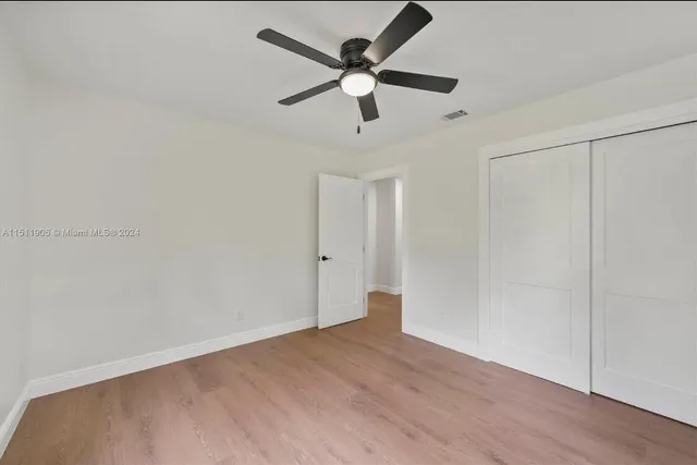 an empty room with wooden floor and ceiling fan