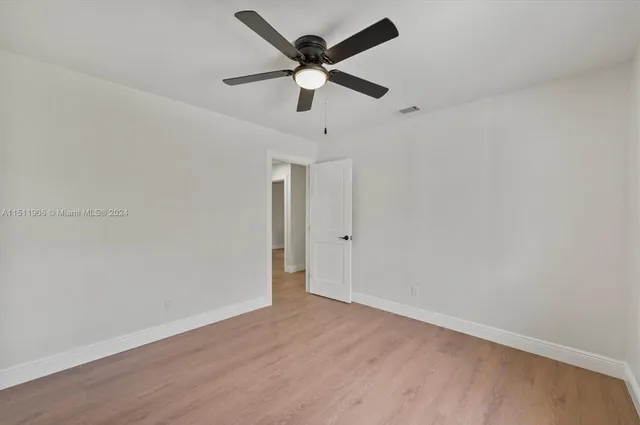 an empty room with wooden floor and ceiling fan