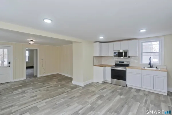 a large white kitchen with kitchen island a sink stainless steel appliances and cabinets