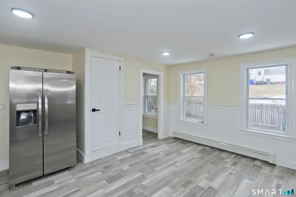 an empty room with wooden floor cabinet and windows