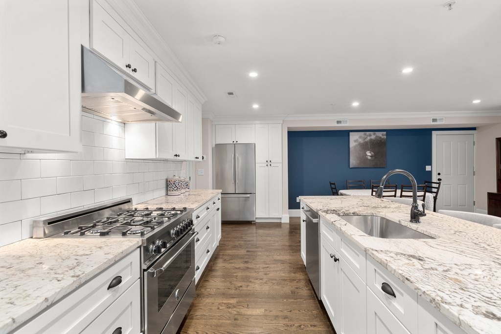 215 Athens Street, Unit 4 Boston, MA 02127 - Photo 4 of 15 a large kitchen with stainless steel appliances granite countertop a lot of counter space and wooden floors