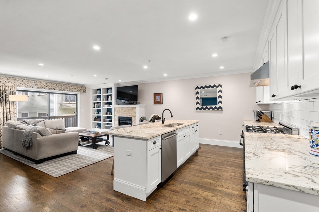 215 Athens Street, Unit 4 Boston, MA 02127 - Photo 5 of 15 a large white kitchen with stainless steel appliances granite countertop a stove and a sink