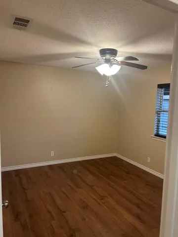 a view of a room with wooden floor and ceiling fan