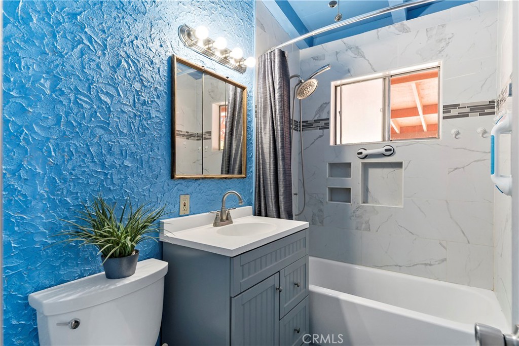 9417 Mango Avenue Fontana, CA 92335 - Photo 25 of 41 a bathroom with a sink a mirror a potted plant and a bathtub