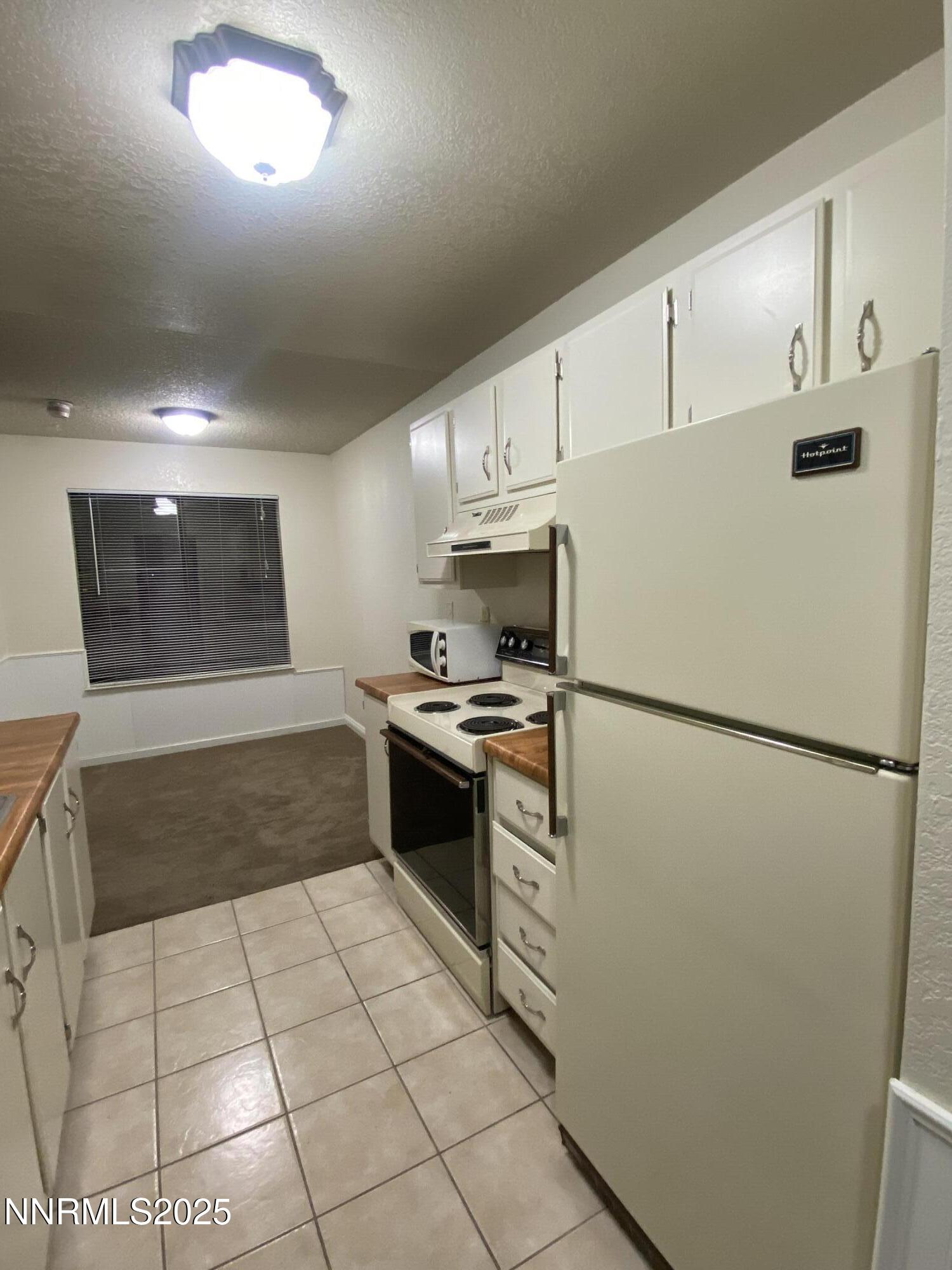 3865 East Leonesio Drive, Unit H1 Reno, NV 89512 - Photo 6 of 12 a kitchen with cabinets and white appliances