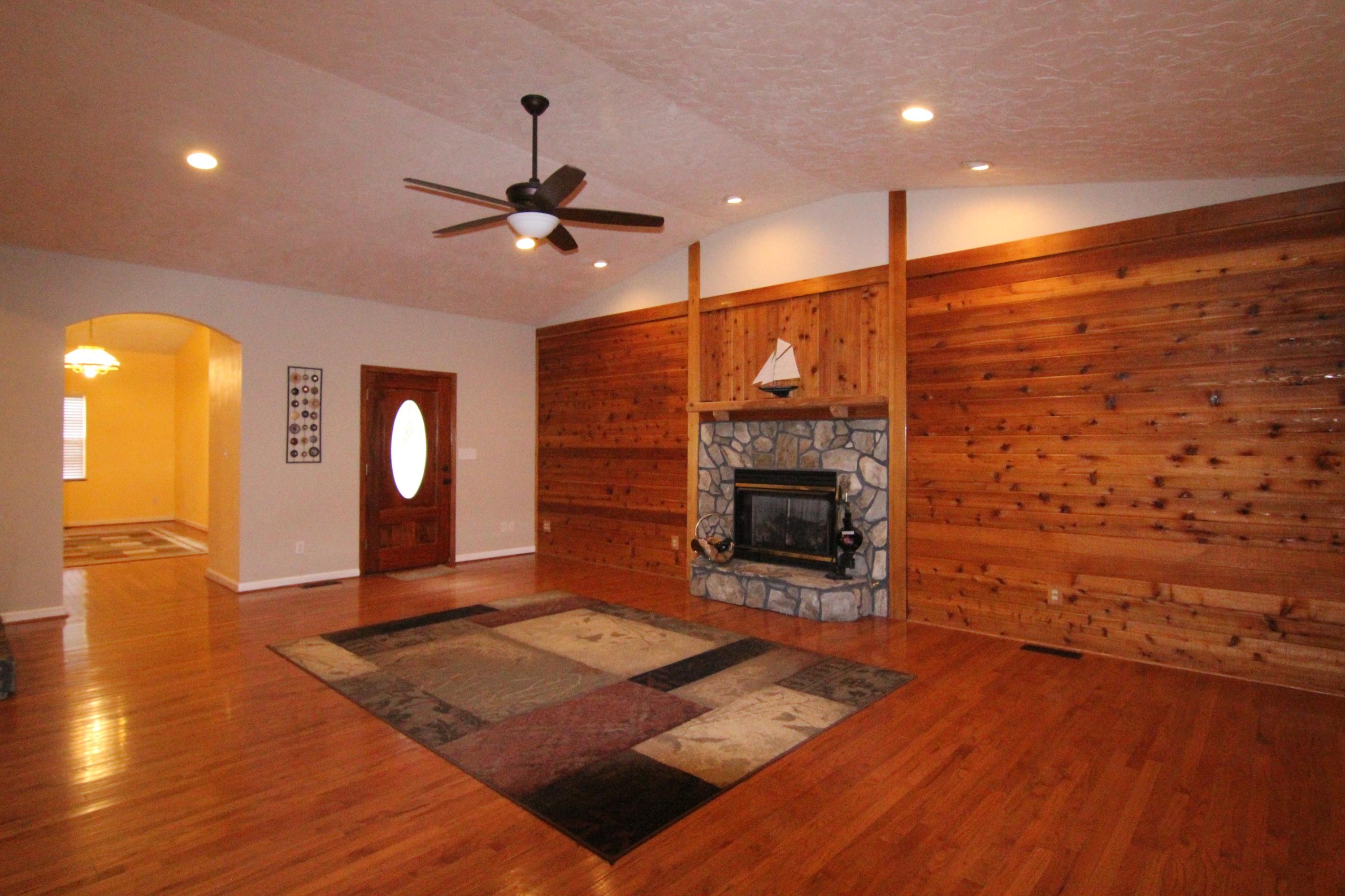 6773 Goodview Road Goodview, VA 24095 - Photo 13 of 43 a living room with a fireplace furniture a ceiling fan and a wooden floor