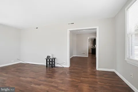 a view of empty room with wooden floor and window