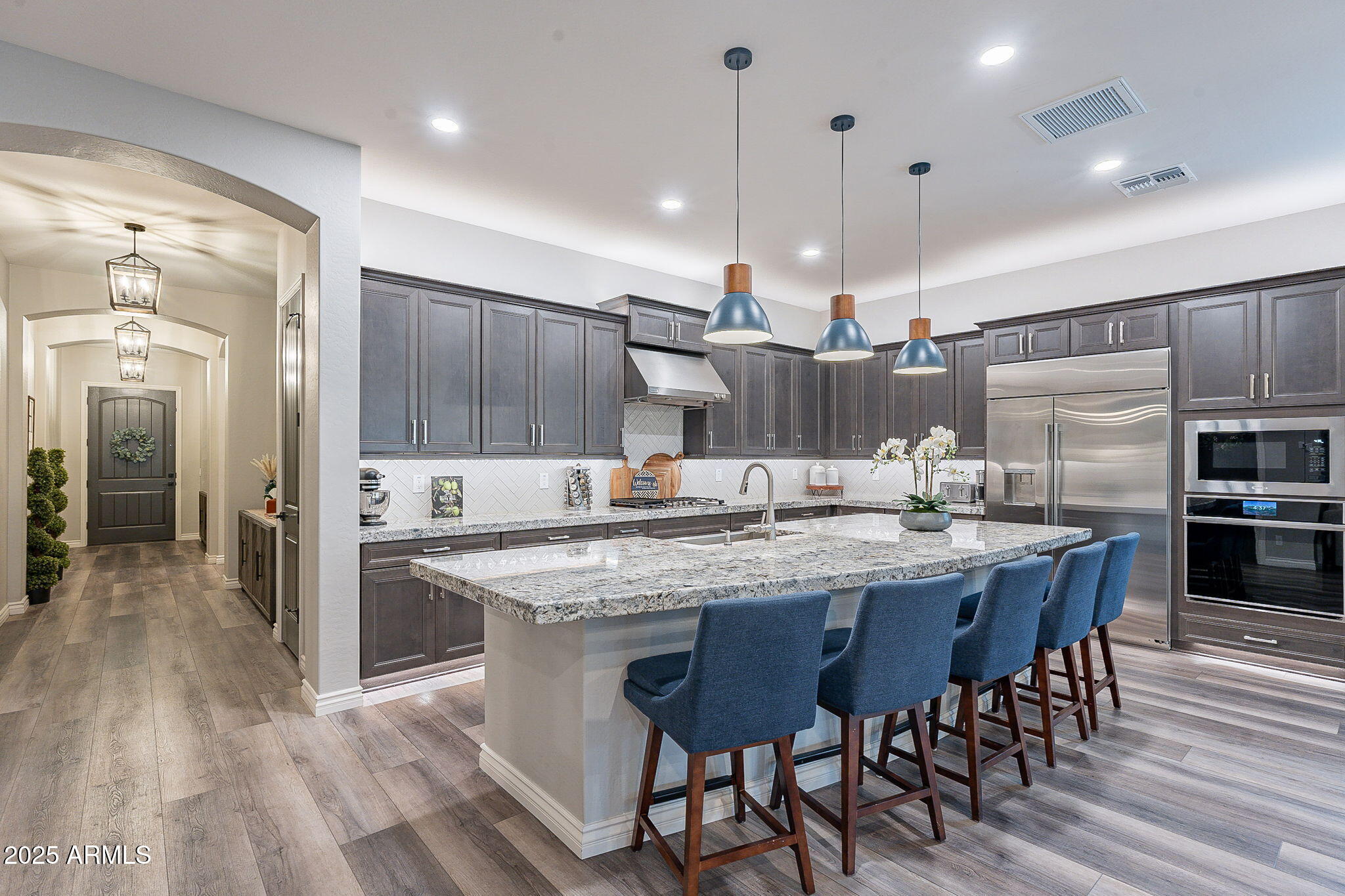 22900 East Reins Road Queen Creek, AZ 85142 - Photo 11 of 74 a kitchen with stainless steel appliances kitchen island granite countertop a table chairs sink and cabinets