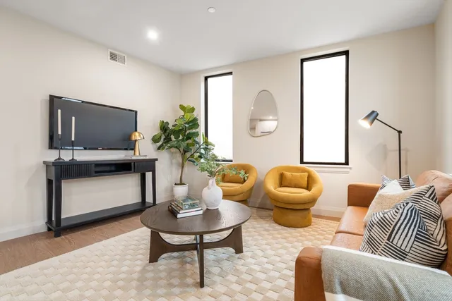 a living room with furniture a flat screen tv and a large window