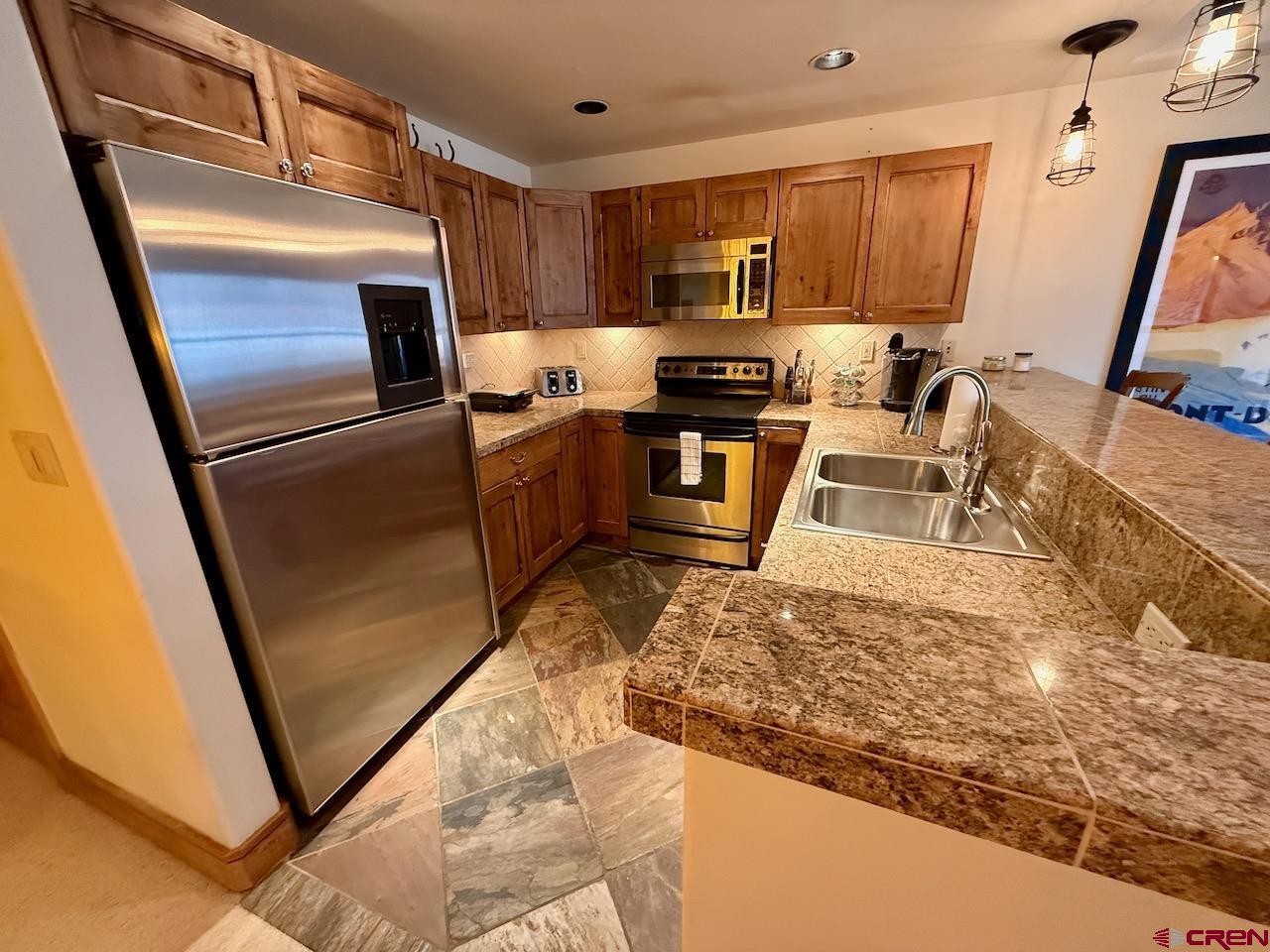 9 Hunter Hill Road, Unit 104 Crested Butte, CO 81225 - Photo 9 of 38 a kitchen with granite countertop a refrigerator a stove top oven a sink and dishwasher