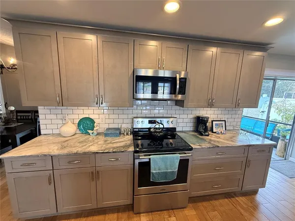 a kitchen with stainless steel appliances granite countertop a stove a sink a microwave a refrigerator and cabinets