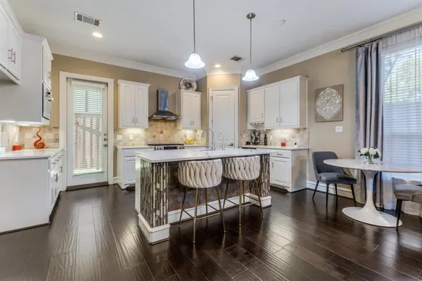 a kitchen with stainless steel appliances granite countertop a stove a sink a refrigerator and white cabinets with wooden floor