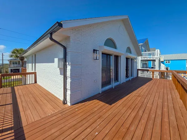 a view of balcony with wooden floor and palm trees