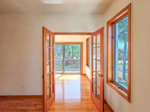 a view of an empty room with glass door and wooden floor