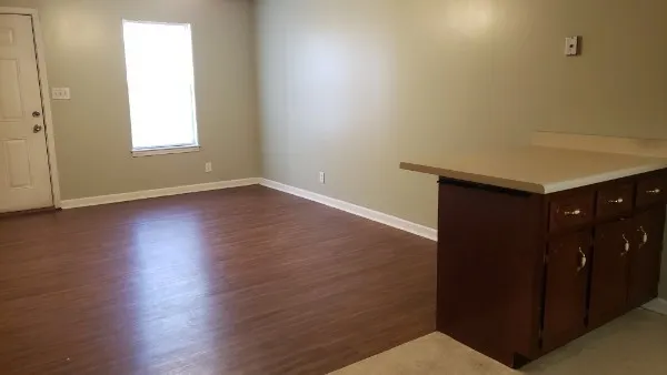 an empty room with wooden floor and windows