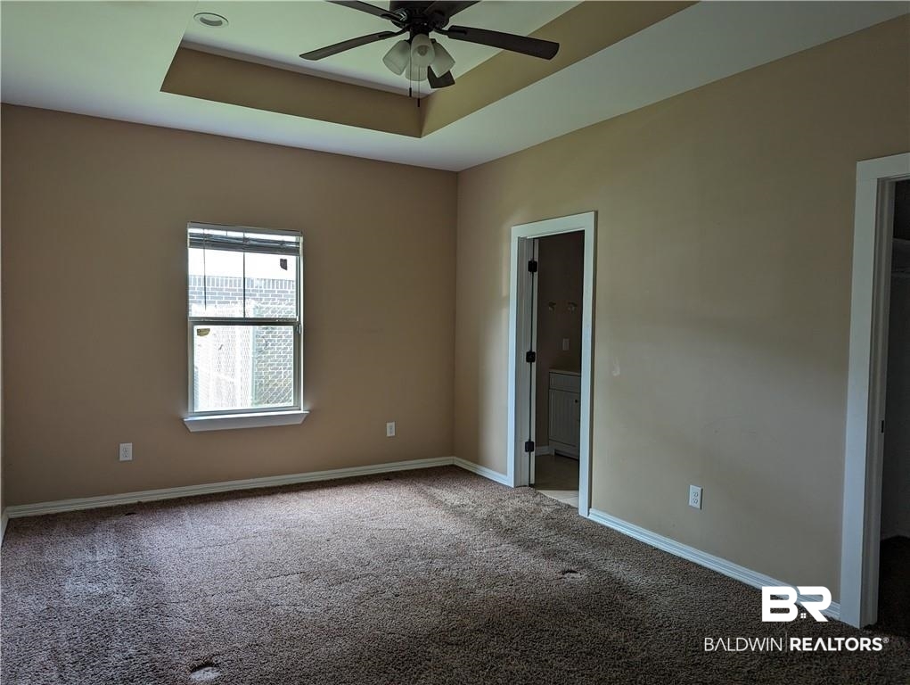 659 Bond Street Mobile, AL 36607 - Photo 7 of 10 Carpeted empty room with ceiling fan and a tray ceiling