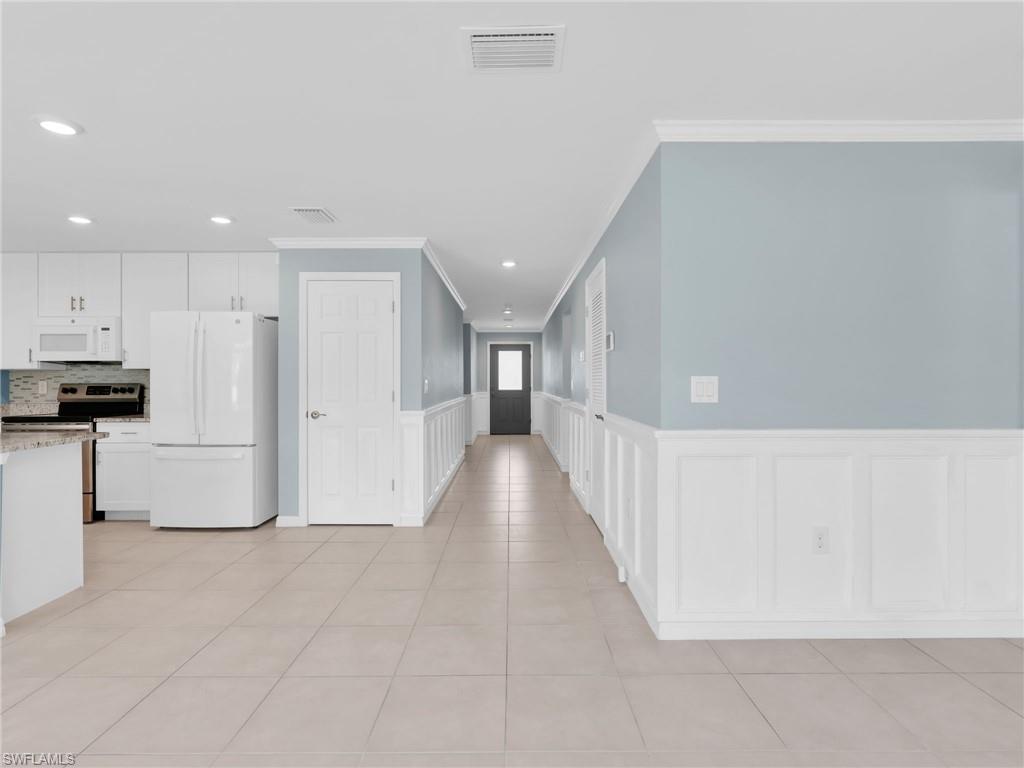 731 Hadley Place West Naples, FL 34104 - Photo 11 of 30 Foyer And Entry Hallway With Crown Molding and Wainscotting, Kitchen With Tile Flooring and New White GE Dishwasher, Microwave, And Refrigerator With Icemaker, And Stainless Steel Frigidaire Range With Self-Cleaning Oven