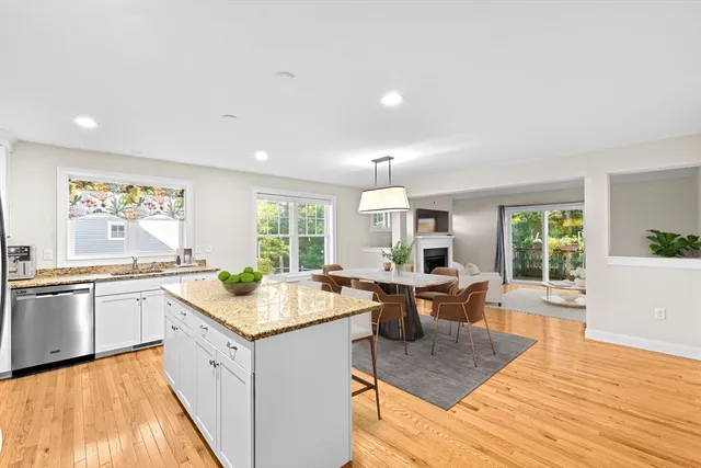 a view of a kitchen counter top space with granite countertop wooden floor and living room view