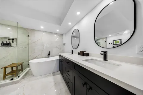 a bathroom with a double vanity sink mirror and bathtub
