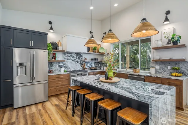 a kitchen with stainless steel appliances granite countertop a stove a sink a oven a dining table and chairs with wooden floor