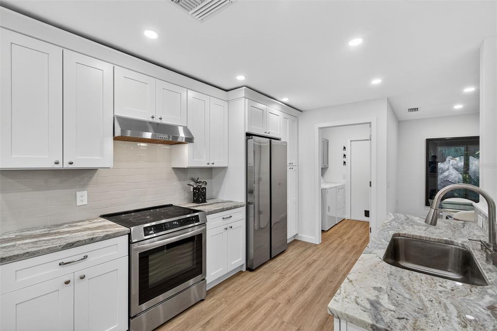 4916 Troon Lane New Port Richey, FL 34655 - Photo 26 of 53 a kitchen with granite countertop a sink stove and refrigerator